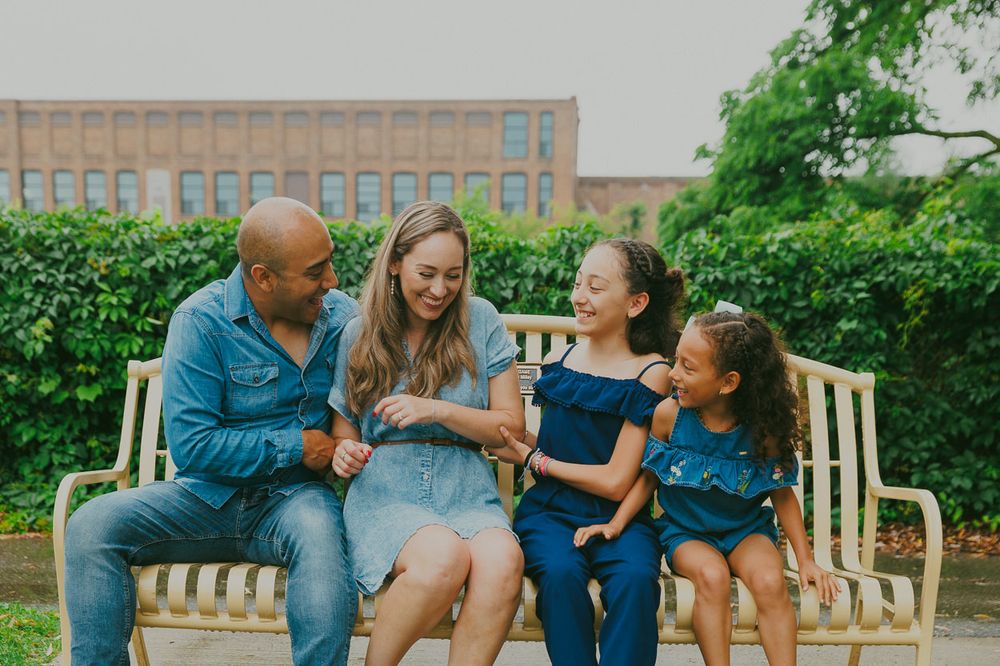 A happy family shares joyful moments while sitting together on a park bench.