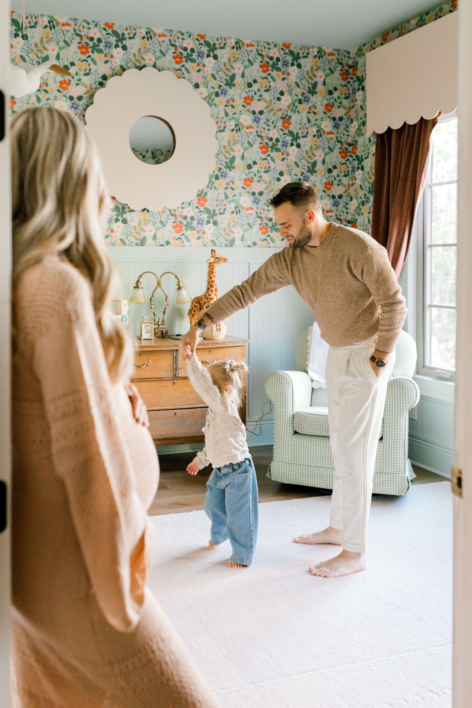 A sweet family moment dancing together in a floral wallpapered nursery.
