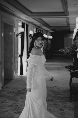 Black and white portrait of someone in an off-shoulder wedding gown in an ornate hallway.
