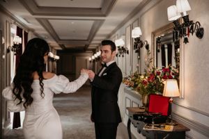 Dancing couple sharing intimate moment in luxurious hotel corridor with vintage lighting.