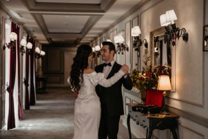 Romantic moment captured in an ornate hallway with classic wall sconces and floral arrangements.