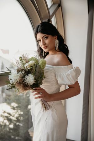 Romantic bridal portrait featuring white floral bouquet and off-shoulder wedding gown.