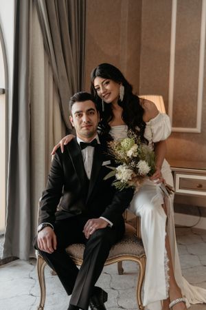 Intimate wedding portrait in vintage-style room with elegant decor and natural window light.