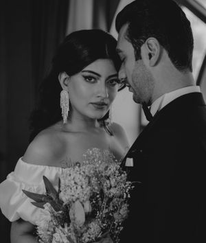 Dramatic black and white wedding portrait with bouquet and formal attire.