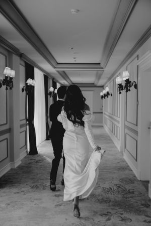 Dynamic shot of newlyweds walking through an elegant corridor with classical decor.