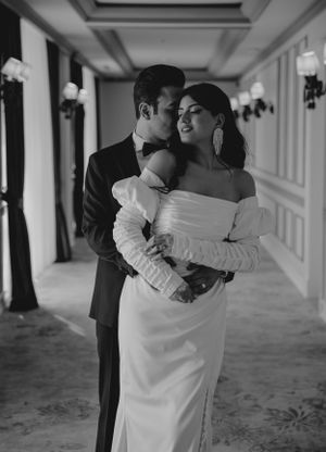 Intimate black and white portrait of a couple embracing in a formal hallway setting.