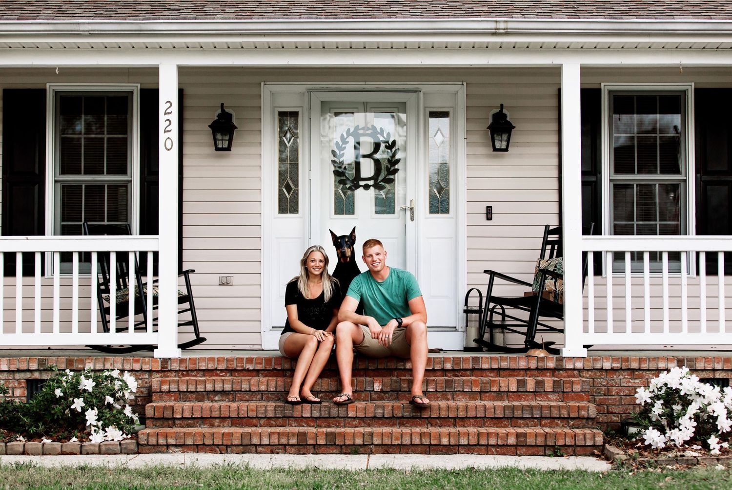 Classic white farmhouse porch with brick steps and hanging lanterns.