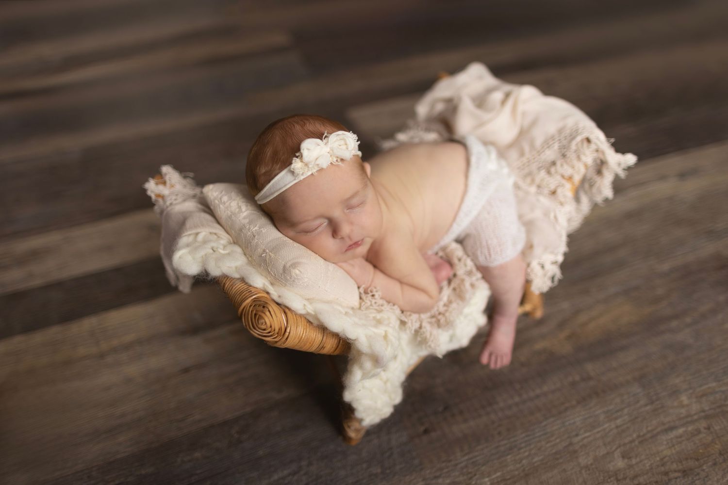 Sleeping infant on cream colored textured blanket with lace accessories.