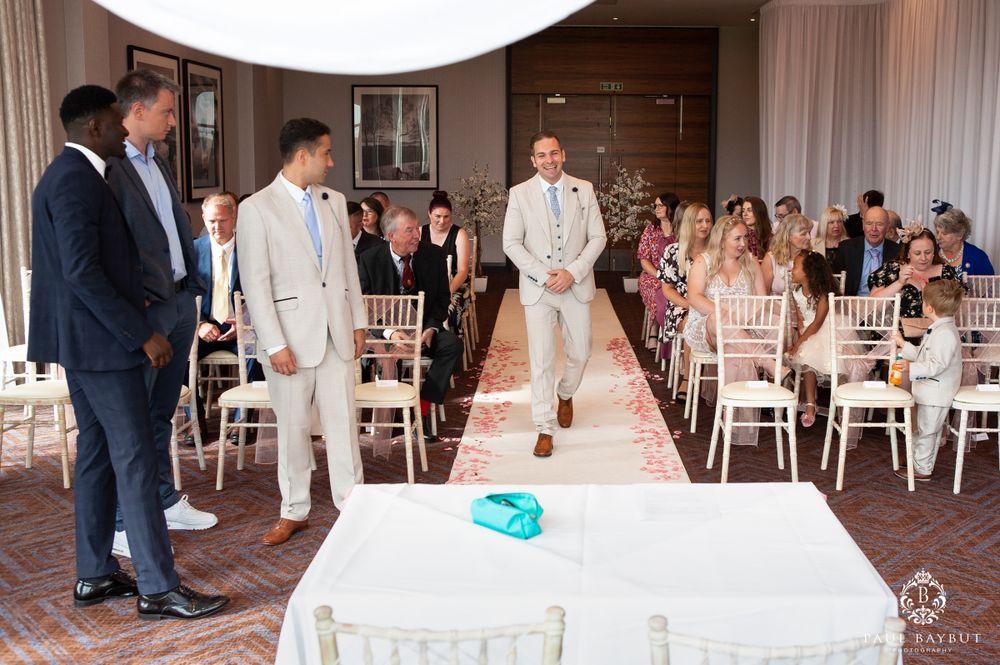 Wedding ceremony setup with white chairs and turquoise accent on aisle runner.