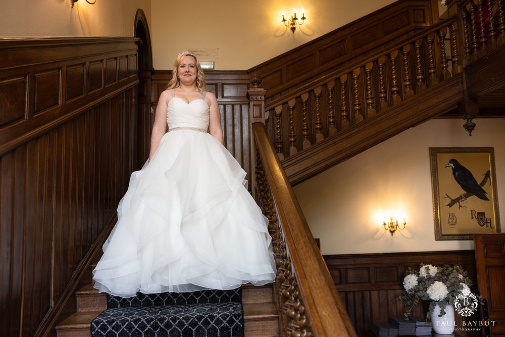 Elegant grand staircase with ornate wooden railings and wall sconces.