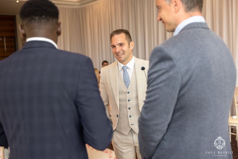 Three people in formal attire having a conversation during a wedding ceremony.