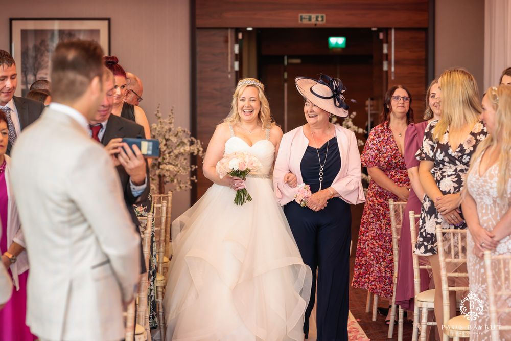 Traditional wedding ceremony in progress inside elegant hotel ballroom with pink walls.