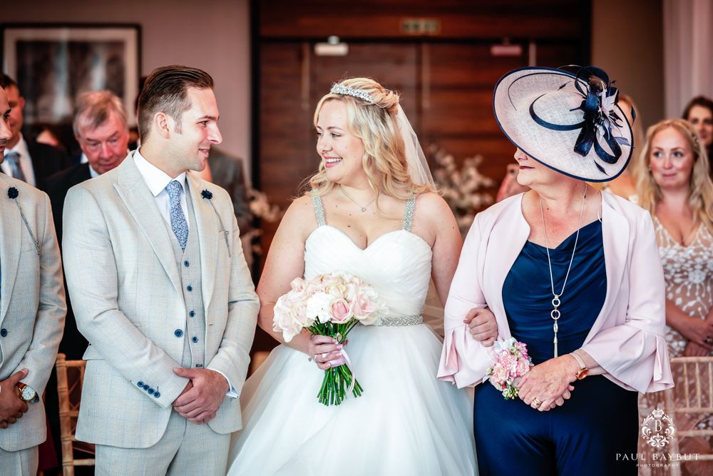 Joyful wedding ceremony moment in elegant ballroom with pink walls and formal attire.