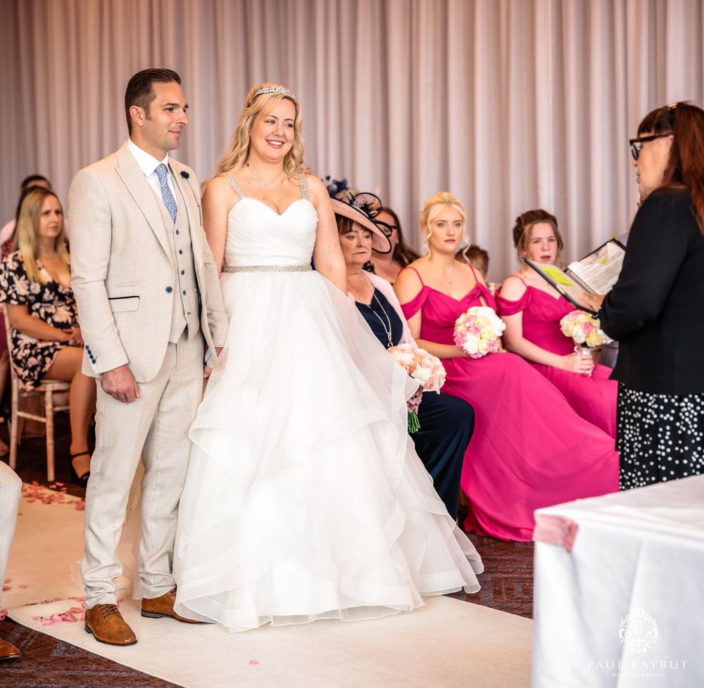 Wedding ceremony in progress with officiant speaking to couple as guests watch from their seats.