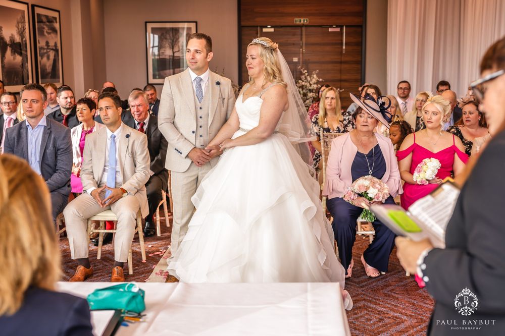 Wedding ceremony in progress with couple standing on white aisle runner as guests look on.