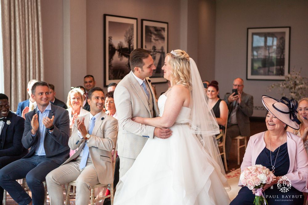 Joyous wedding celebration with guests clapping as couple shares special moment at ceremony.