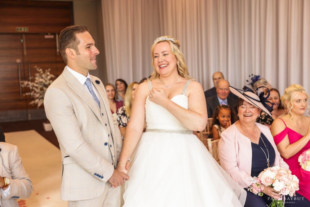 Newlyweds share a happy moment during their indoor wedding ceremony.