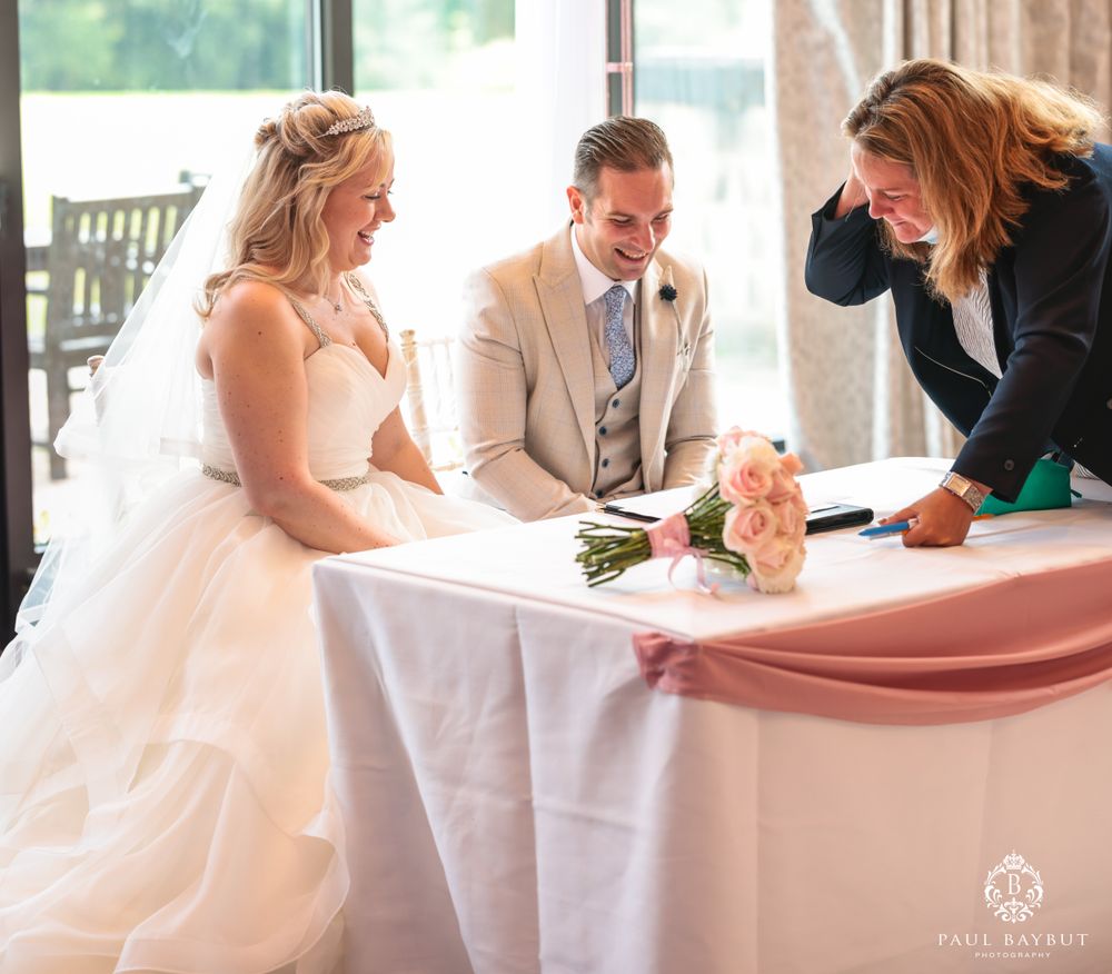Couple reviews and signs wedding paperwork at decorated table with officiant.