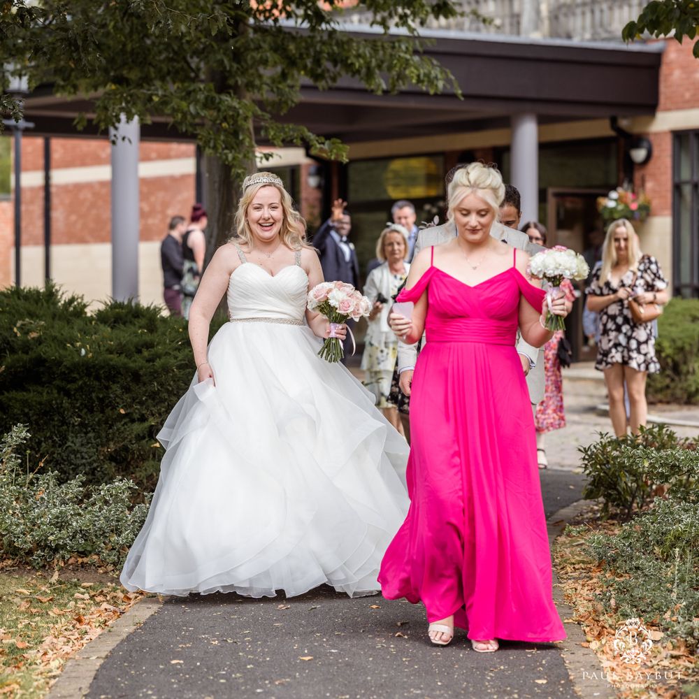 Wedding group walking together on path with bright pink and white formal attire.