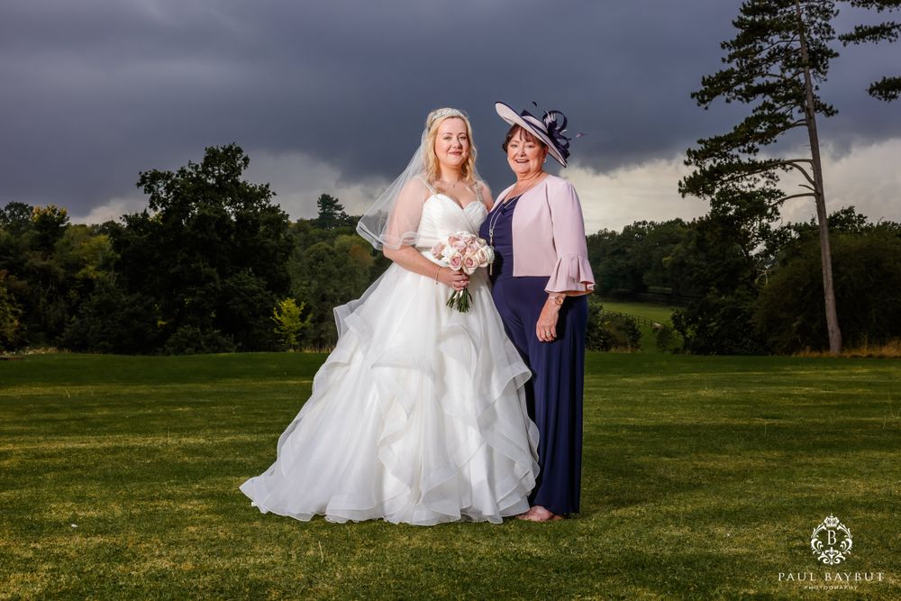 An outdoor wedding portrait with stormy skies and tall pine trees in the background.