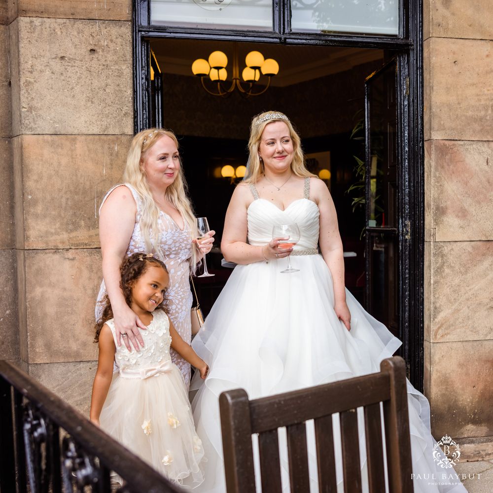 A beautiful wedding celebration on stone steps with elegant white gowns and vintage lighting overhead.