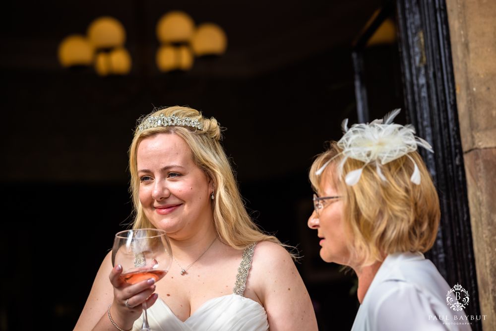 Wedding guests share a candid moment with wine glasses while enjoying the celebration under vintage lighting.