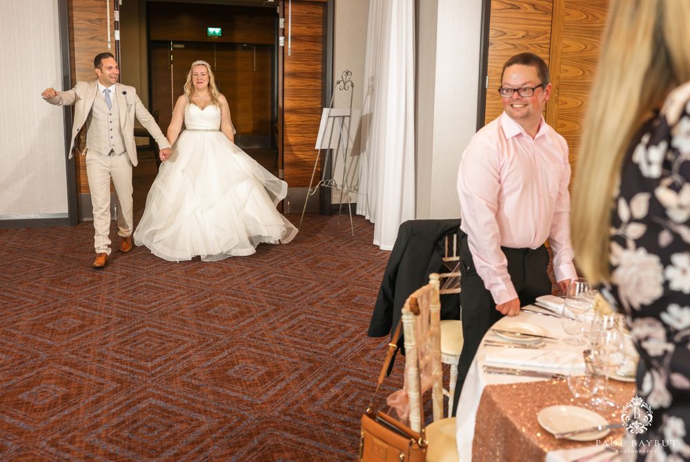 Wedding entrance scene with couple making grand entrance while staff prepare.