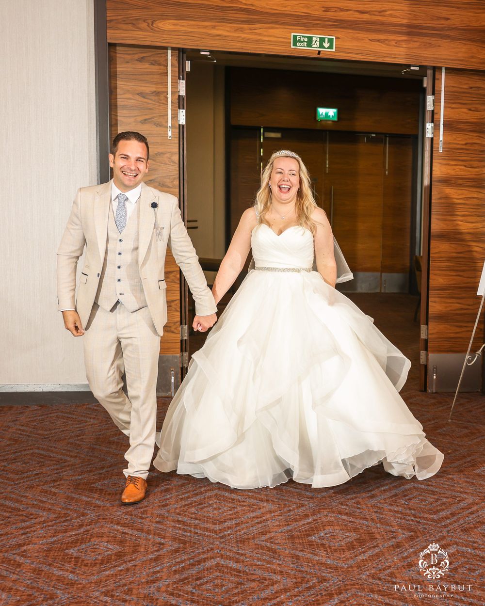 Joyful scene of couple entering their wedding reception through wooden doors.