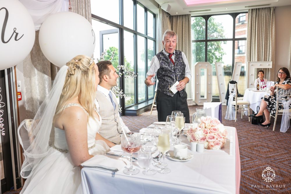 Wedding reception scene with large white balloons and floral centerpieces at a head table.