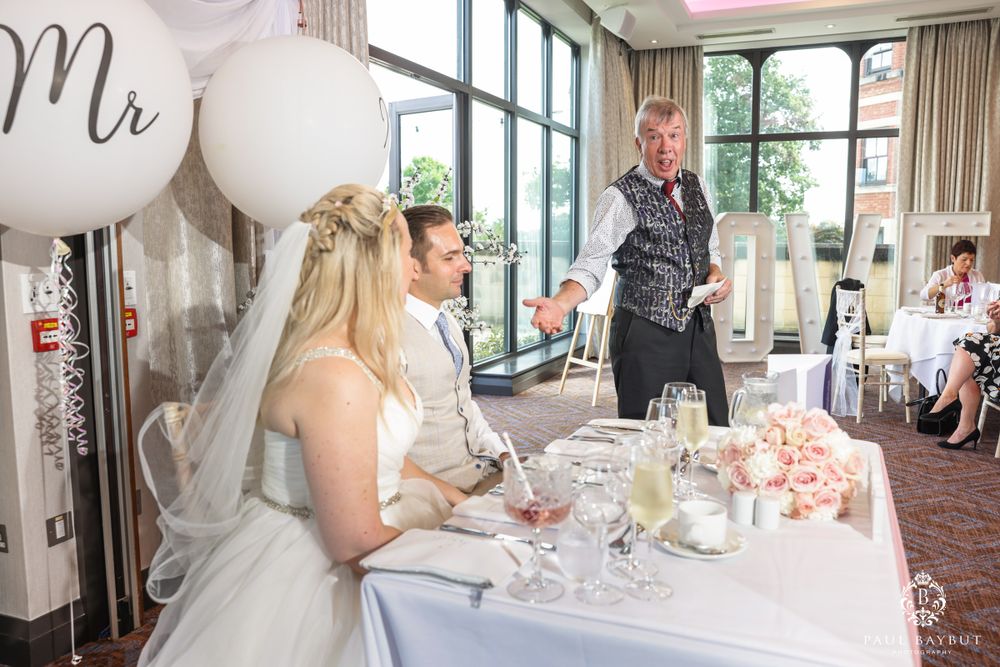 A formal reception with white balloons and table decor in an elegant room with floor-to-ceiling windows.