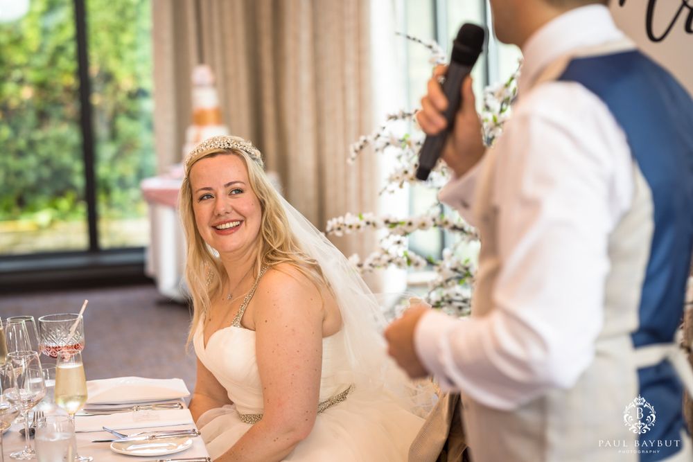 Candid moment during wedding speeches at an elegant indoor reception.