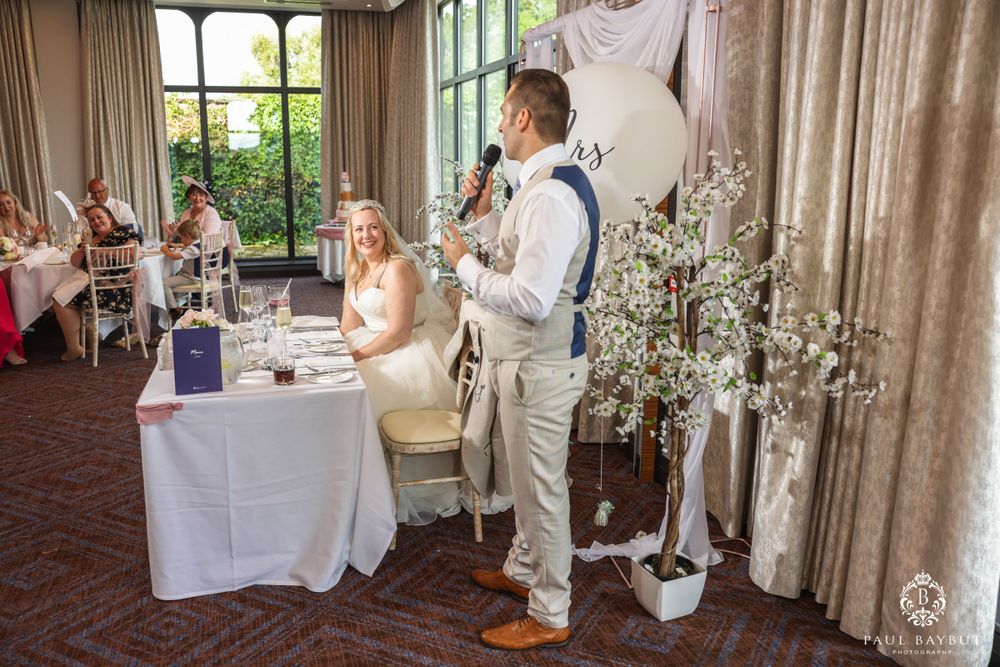 Wedding reception venue with decorative trees and elegant white draping.