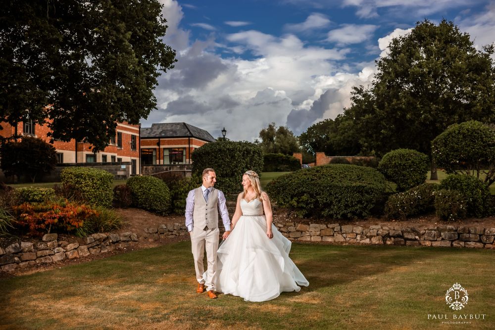 A couple walks through a manicured garden during their wedding photoshoot.
