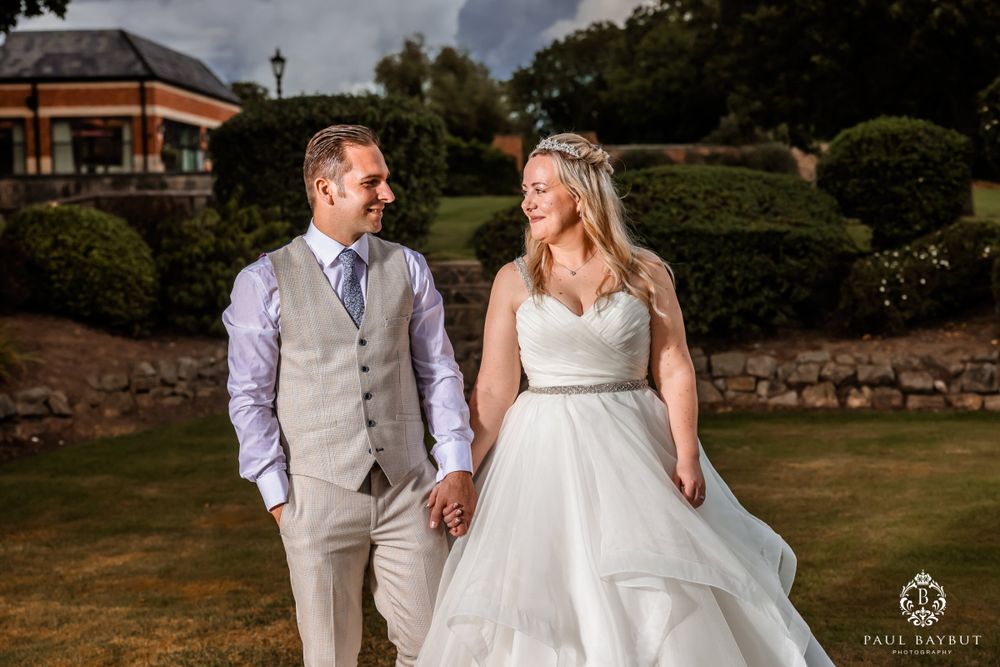 A couple shares a romantic moment on their wedding day in a sunlit garden setting.