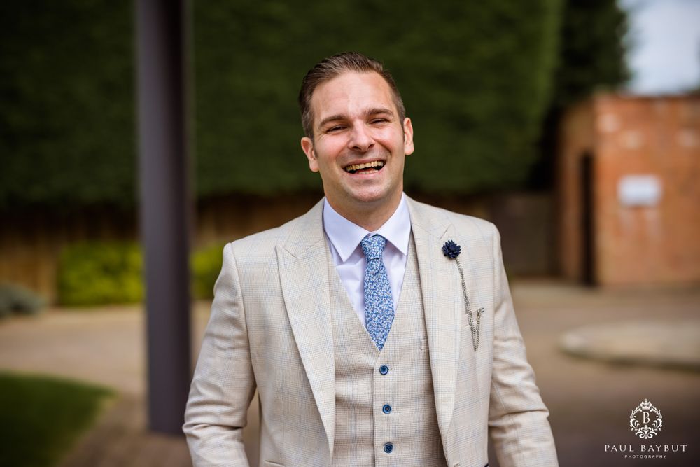 Person wearing light gray three-piece suit with blue tie standing outdoors.