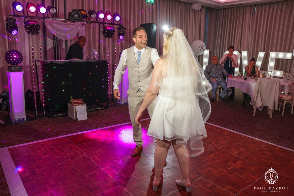 A couple dances on a purple-lit dance floor during their wedding reception.