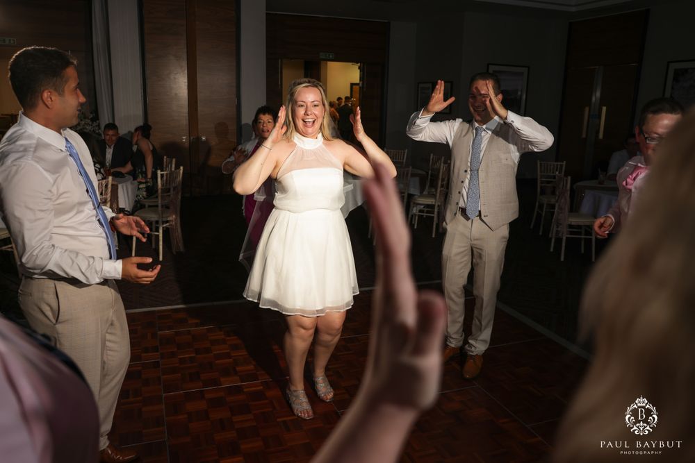 Wedding guests dancing enthusiastically on the dance floor during a fun reception celebration.