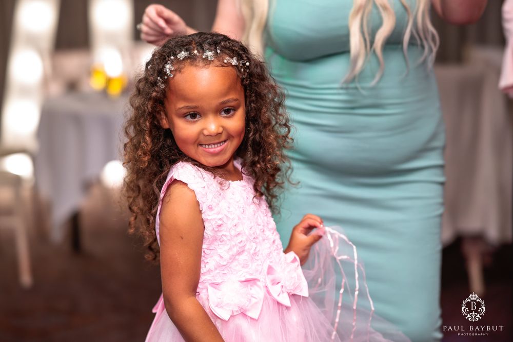 Young guest in pink dress smiling brightly during wedding celebration.