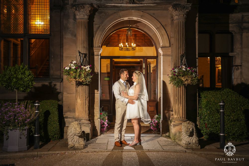 Romantic evening portrait of couple under lit stone archway entrance.