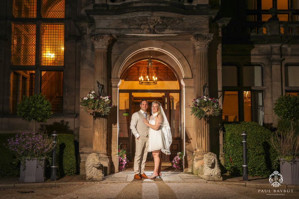 Couple sharing intimate moment under illuminated stone archway at night.