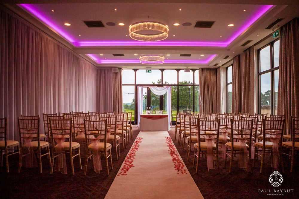 Elegant wedding ceremony setup with purple lighting and chiavari chairs in a modern venue.