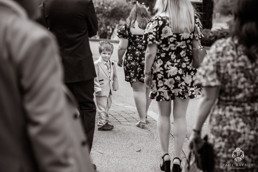 Black and white candid shot of wedding guests and small child at outdoor event.