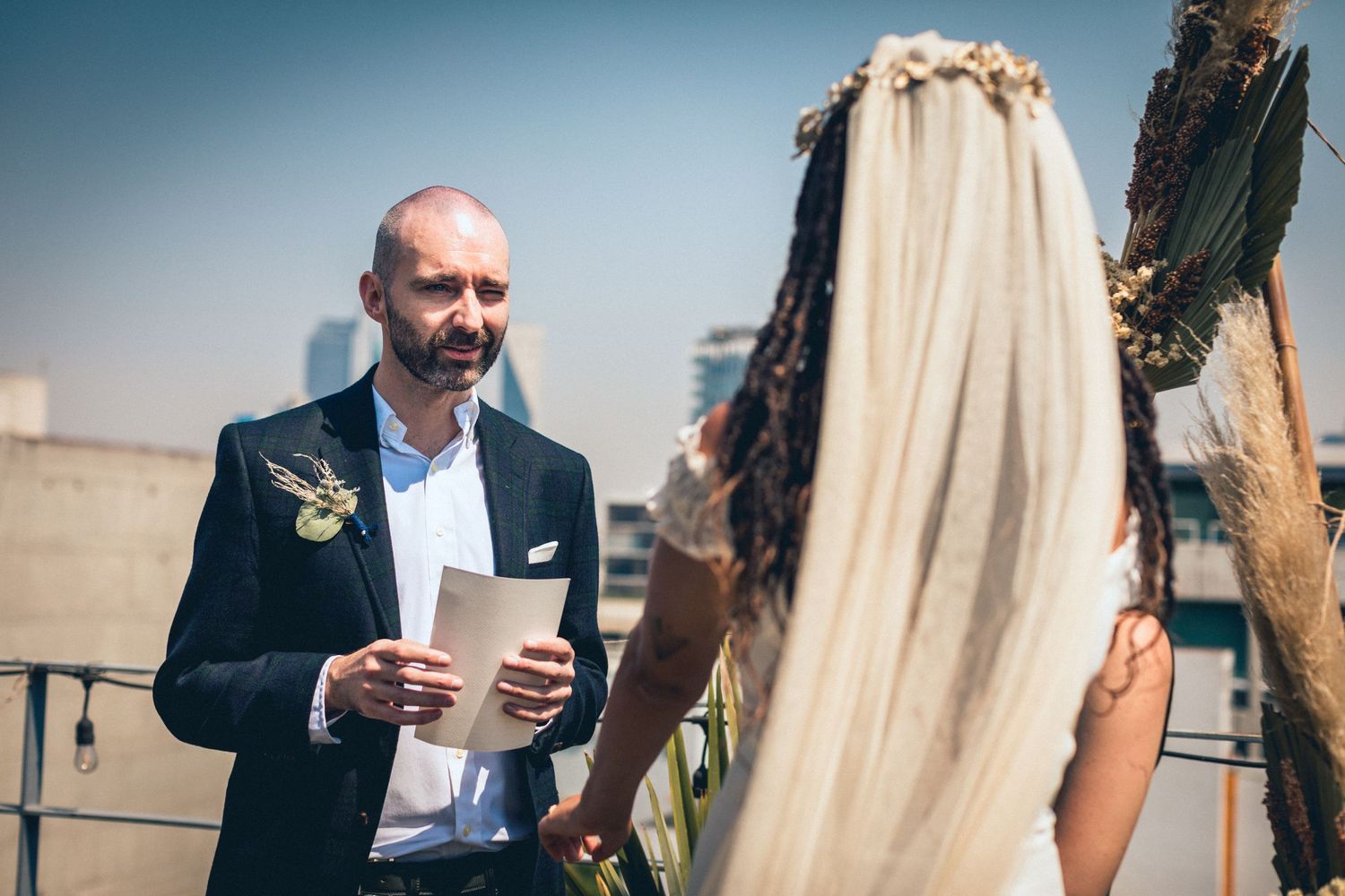 Wedding guests mingling and socializing at an outdoor rooftop reception.