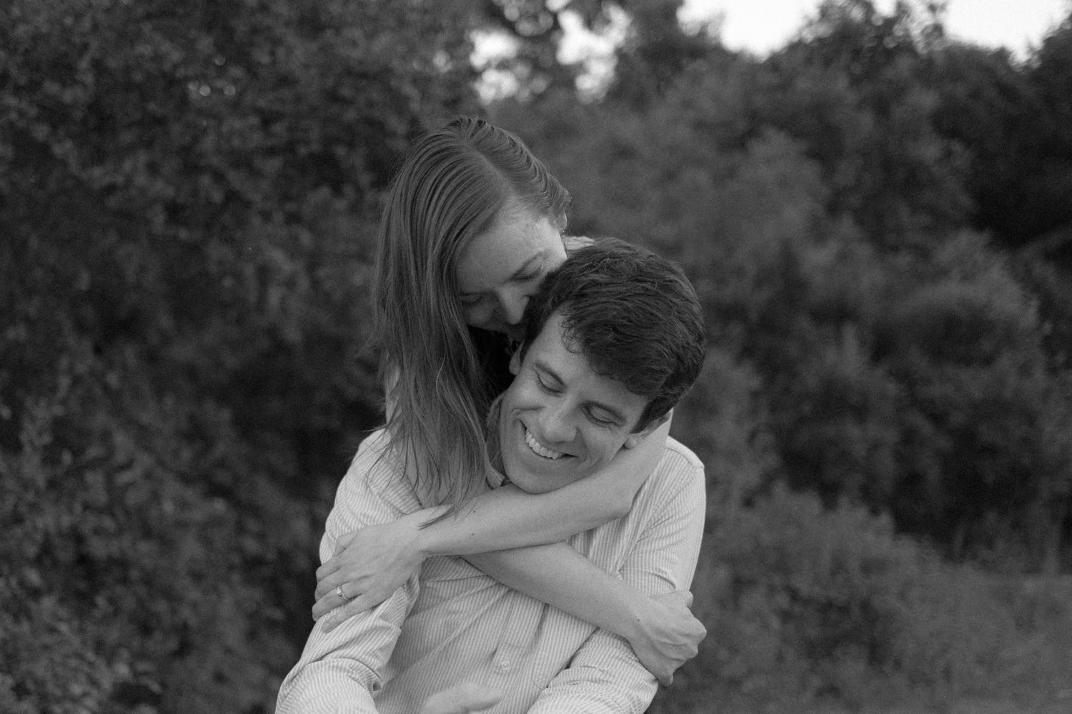 Black and white intimate portrait of couple sharing tender moment outdoors.