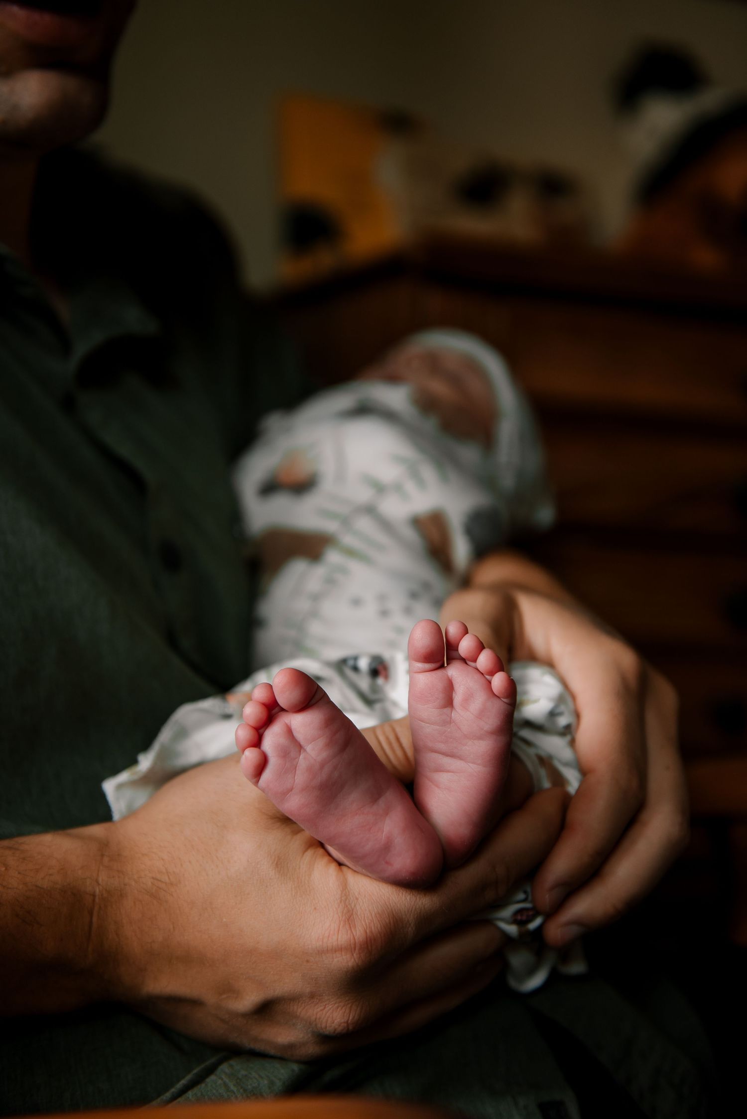 Intimate close-up of tiny newborn feet resting in gentle hands.