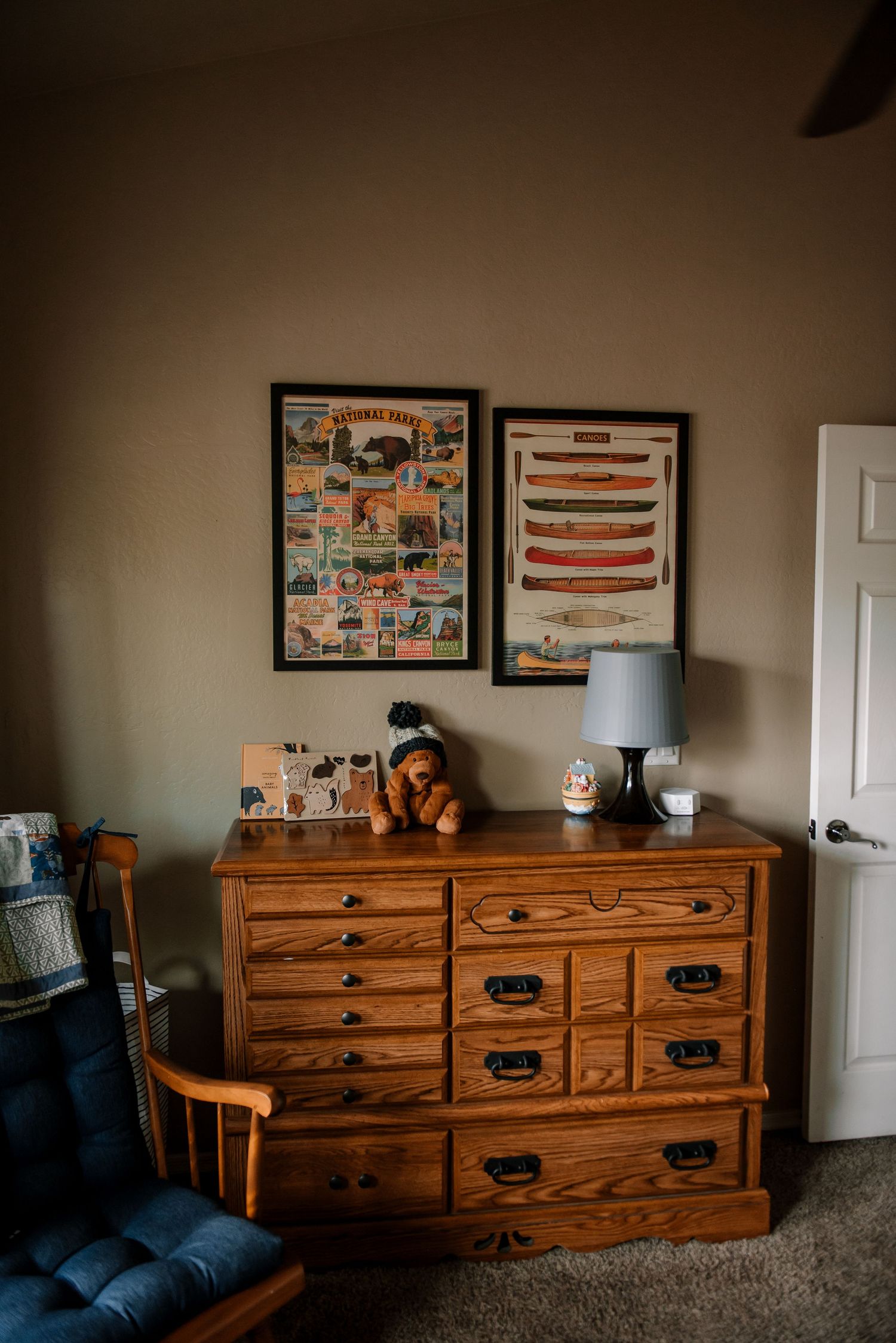 Wooden dresser with framed artwork displayed in a cozy nursery setting.