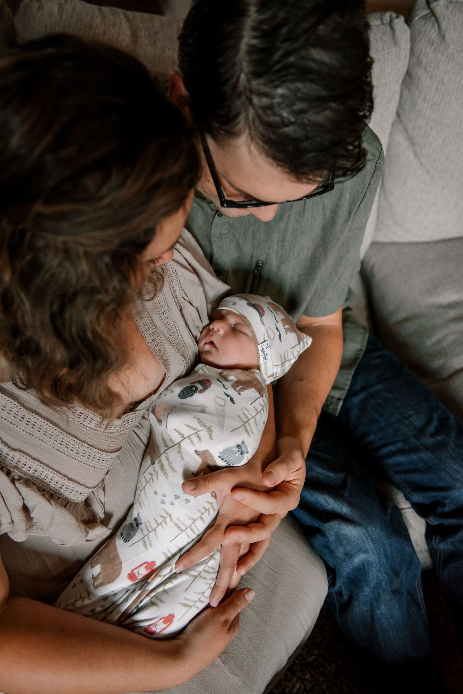 Parent tenderly holding and gazing at newborn baby wrapped in patterned blanket.