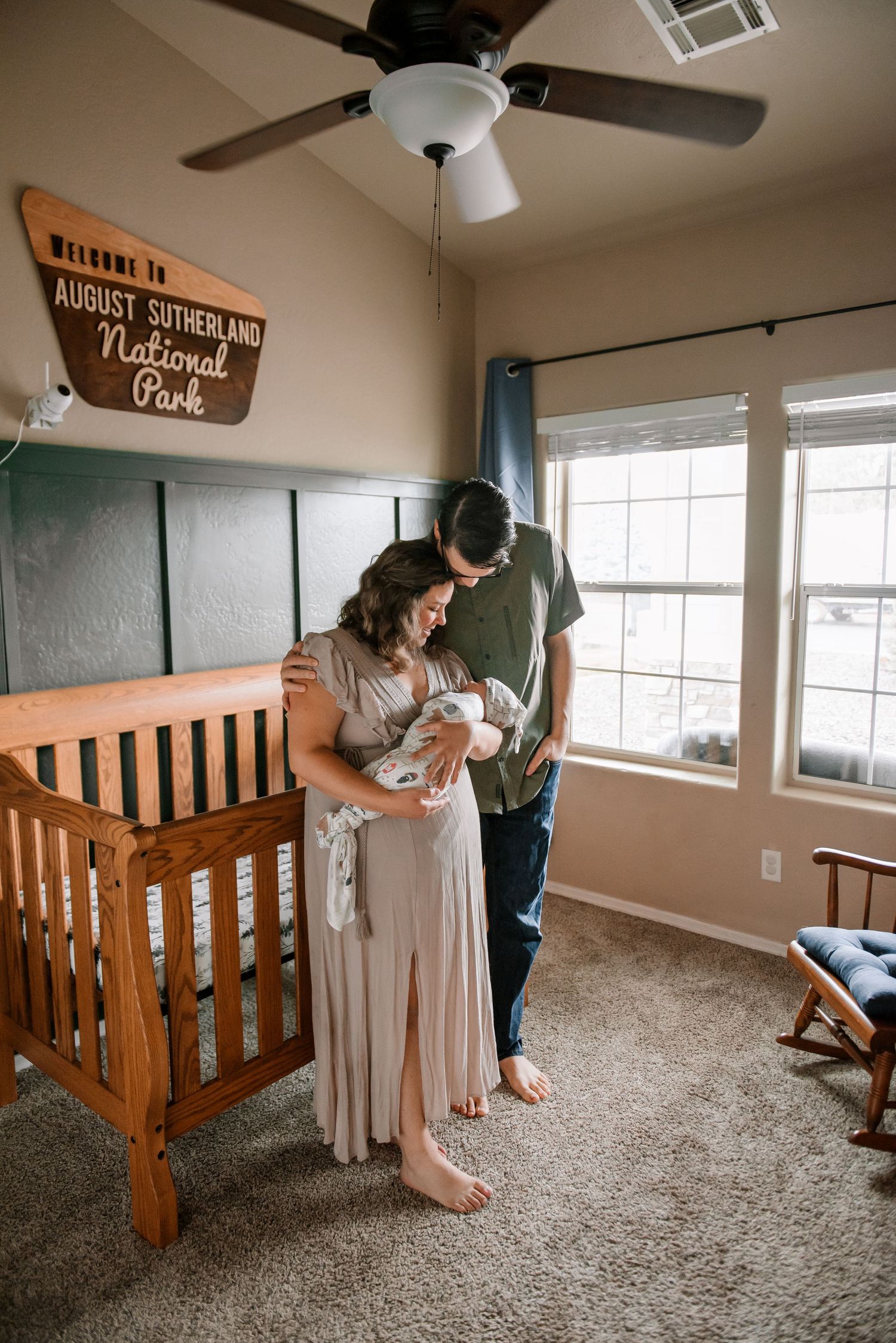 Nursery room with wooden crib and natural lighting from windows.