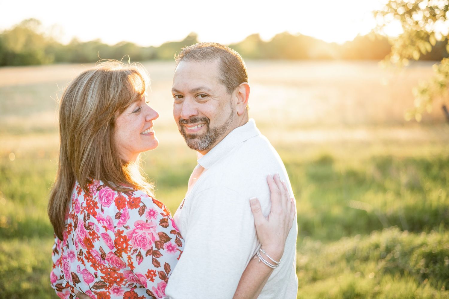 A couple shares an intimate moment in a sunny field during golden hour.
