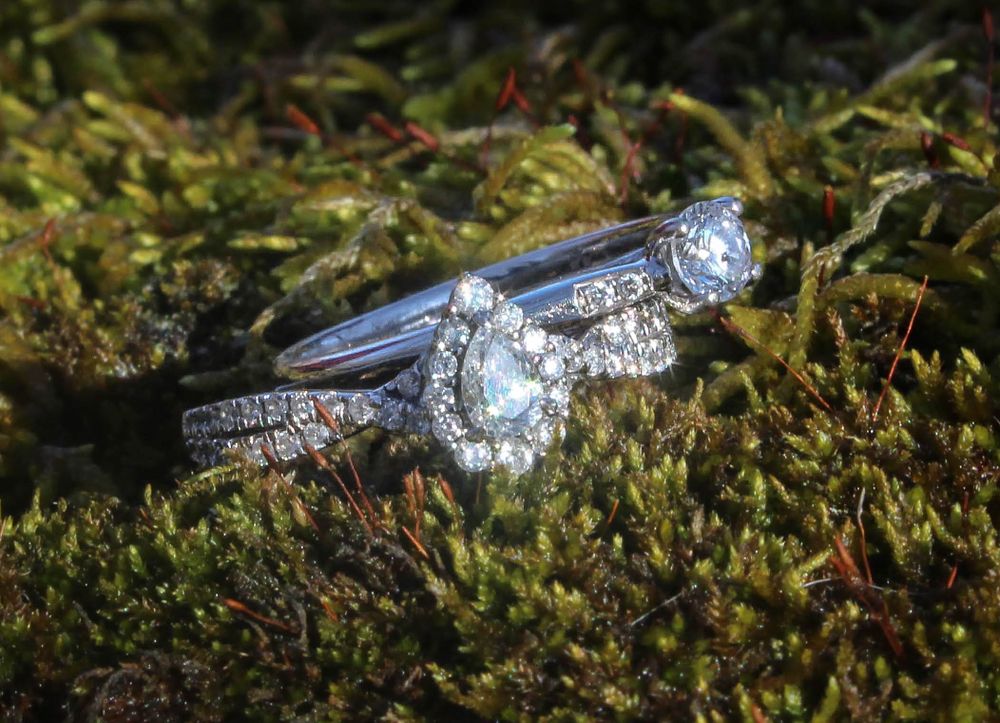 Diamond engagement ring and wedding band set photographed on green moss in natural light.